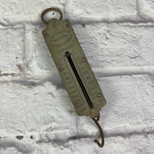 May include: A vintage silver Chatillon's Improved Package Scale with a hanging hook. The scale has a dial with markings from 0 to 2000 grams.