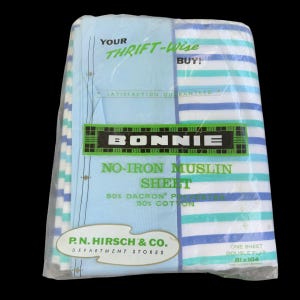 May include: A packaged Bonnie no-iron muslin sheet, with blue, white, and teal stripes. The packaging includes text that reads "Your Thrift-Wise Buy!" and "Satisfaction Guaranteed." The sheet measures 206x264 cm.