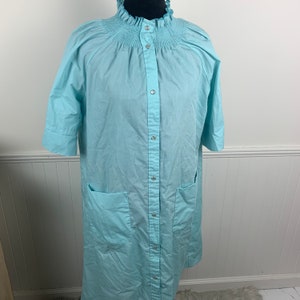 May include: A light blue button-up robe with a ruffled collar and two pockets. The robe has a gathered elastic band at the neckline.