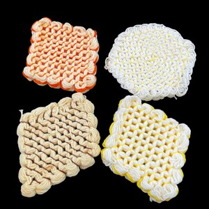 May include: Four crocheted coasters in different patterns and colors. One is orange and white, one is white with a flower pattern, one is cream with brown accents, and one is white with yellow accents.