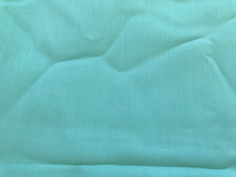 K&ouml;nnte beinhalten: Ein glatter, hellblauer Stoff mit einer dezenten Textur. Der Stoff ist gefaltet und hat einen leichten Glanz.