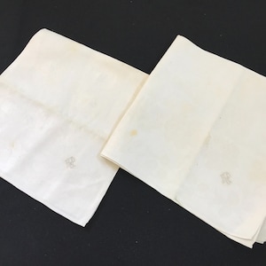 May include: Two white linen napkins with the letter "R" embroidered in the corner.