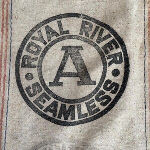 May include: A vintage burlap sack with a black and white circular logo that reads "Royal River Seamless" with a large letter "A" in the center.