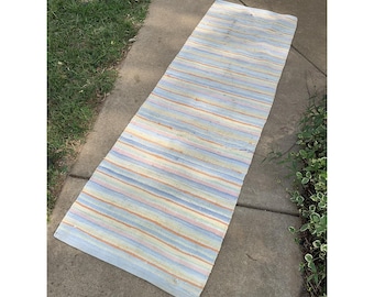 Alfombra o tapete tejido vintage con rayas multicolores y flecos.