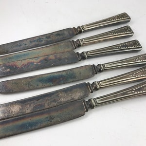 Peut inclure: Ensemble de six couteaux de table en argent plaqué avec des manches ornés. Les couteaux ont un aspect vintage et sont légèrement ternis.