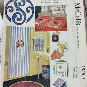 May include: McCall's Transfer Pattern 1945 L, a blue transfer pattern for embroidery. The pattern includes four 6-inch and two 12-inch scroll initials. The pattern is shown on a variety of household items, including towels, a shower curtain, a rug, and a wastebasket.