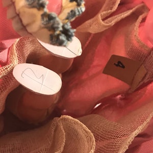 May include: Close-up of a pink dress with a tulle overlay. The dress has a number "2" written on one leg and a number "4" written on the other leg.