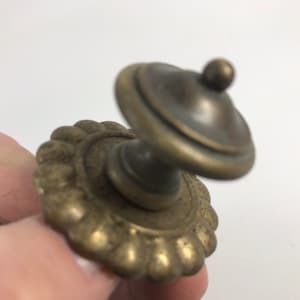 May include: A brass cabinet knob with a decorative, scalloped base and a round, domed top.