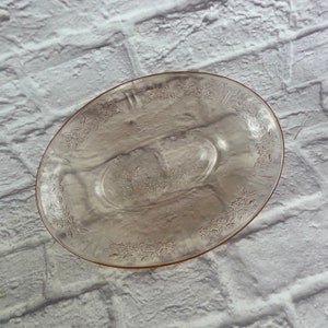 May include: A vintage pink glass divided serving dish with a floral pattern. The dish has a raised rim and two separate compartments.