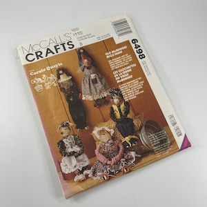 May include: A vintage McCall's Crafts sewing pattern for making a set of five farmhouse-style dolls. The pattern is titled "Old McBungee Bells Farm" and features a colorful illustration of the dolls. The pattern number is 6498.