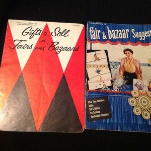 Puede incluir: Dos libros de bolsillo vintage con cubiertas rojas, blancas y negras. El libro de la izquierda tiene el título "Gifts to Sell at Fairs and Bazaars". El libro de la derecha tiene el título "fair & bazaar Suggestions".