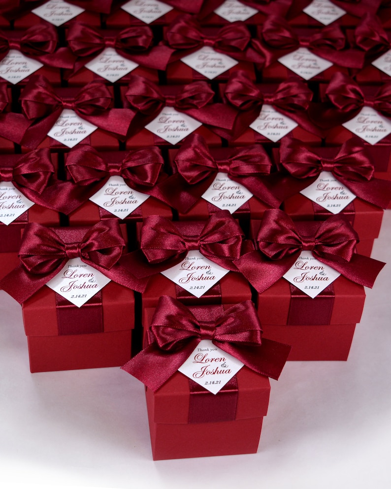 K&ouml;nnte beinhalten: Weinrote Geschenkboxen mit wei&szlig;en Satinb&auml;ndern und personalisierten Etiketten mit der Aufschrift "Danke Loren & Joshua 2.14.21".
