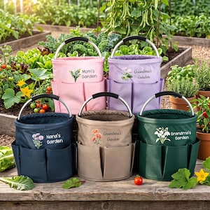 Könnte beinhalten: Fünf zylindrische Gartentaschen mit Metallgriffen und Außentaschen. Die Taschen sind rosa, lila, marineblau, beige und dunkelgrün. Jede zeigt eine Blumenillustration und den Text Mom's Garden, Grandma's Garden oder Nana's Garden.