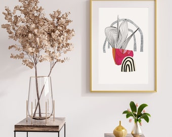 May include: A gold framed print with a white background and a black and white abstract design with a red and pink shape in the centre. The print is hanging on a white wall above a brown wooden table with a clear glass vase with dried branches and a gold vase with a small bouquet of flowers.