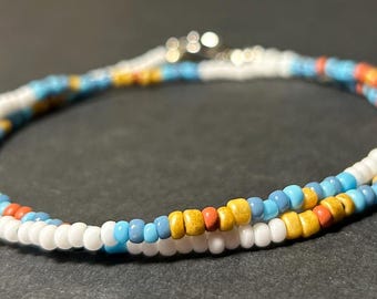 May include: A white, blue, yellow, and orange beaded necklace with a silver clasp.