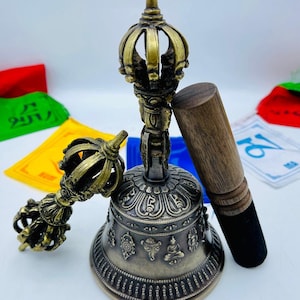 May include: A set of two Tibetan singing bowls, one large and one small, with a wooden striker. The bowls are made of brass and have intricate designs. The larger bowl has a crown-shaped top.