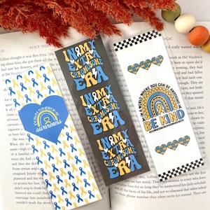 May include: Three colorful bookmarks with a rainbow, yellow and blue ribbons, and the text "In My Extra Chromosome Era" and "Be Kind #downsyndromeawareness".