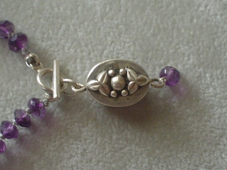 May include: A silver necklace with a decorative clasp and purple amethyst beads.