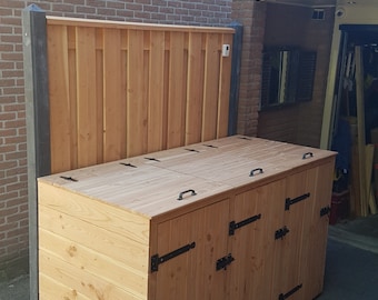 May include: A wooden outdoor storage bin with three compartments and hinged doors. The bin is made of light brown wood with black metal hinges and handles. The bin is sitting on a black patio.