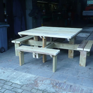 Op de afbeelding: Een houten picknicktafel met vier banken. De tafel is gemaakt van natuurlijk hout en heeft een vierkant blad. De banken zijn aan de tafel bevestigd en zijn ook gemaakt van natuurlijk hout.