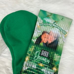May include: Green and white memorial socks with a photo of a woman and child. The socks have the text "In Loving Memory Of Amber Deamin" and the dates "Sunrise 07/07/86" and "Sunset 11/10/19".