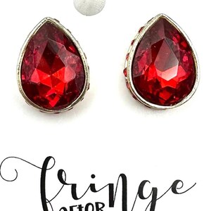 May include: A pair of red teardrop-shaped earrings with a silver setting. The earrings are on a white background with the text "Fringe After Dark" written in black.