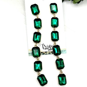 May include: A pair of long, dangling earrings with multiple emerald green rectangular stones and gold accents.