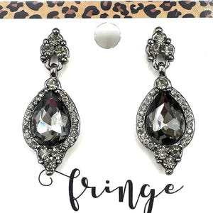May include: A pair of dangle earrings with a teardrop-shaped, faceted gray stone center, surrounded by small clear crystals. The earrings are set in a silver-tone metal and are displayed on a white card with the word "fringe" in cursive.