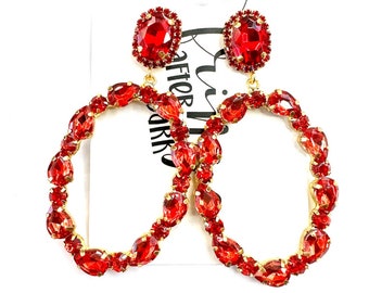 May include: A pair of red crystal hoop earrings with a large red crystal drop on each earring.