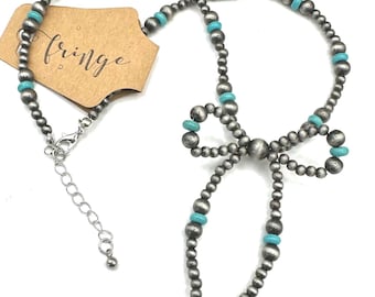 May include: A silver necklace with turquoise beads and a bow accent. The necklace is made of metal beads and has a silver chain clasp.