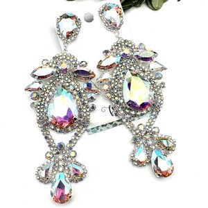 May include: A pair of dazzling, silver-toned chandelier earrings. Each earring features a large, iridescent teardrop-shaped crystal surrounded by smaller, sparkling stones. The design includes multiple tiers of crystals, creating a glamorous and eye-catching accessory.