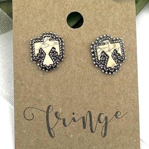 May include: A pair of silver earrings with a white stone in the shape of a bird. The earrings are on a brown card with the word "fringe" written on it.