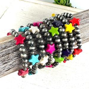 May include: A set of colorful star-shaped bead bracelets. Each bracelet features a different color star bead, including pink, green, yellow, blue, purple, and white. The bracelets are made with silver-toned beads.