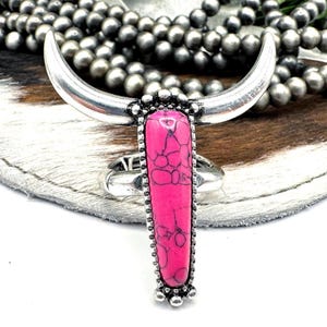 May include: A silver ring with a pink stone in the shape of a bull's head.