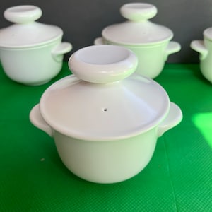 May include: Set of four white ceramic ramekins with lids. Each ramekin has a small hole in the lid.