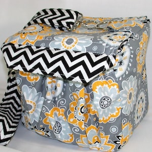 May include: A gray and white chevron patterned fabric bag with a yellow floral print. The bag has a black and white chevron patterned strap.