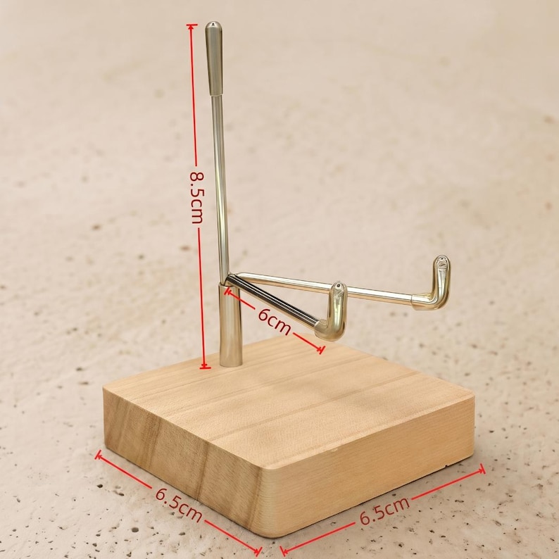 Op de afbeelding: Een houten displaystandaard met een zilveren metalen houder. De houten basis meet 6,5 cm x 6,5 cm. De metalen houder is 8,5 cm hoog en 6 cm breed. De standaard is ontworpen om een item vast te houden.