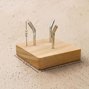 Op de afbeelding: Een houten bureau-organizer met drie metalen penhouders. De houten basis meet 6,5 cm x 6,5 cm en de penhouders zijn 3,3 cm hoog. De organizer is gemaakt van lichtgekleurd hout.