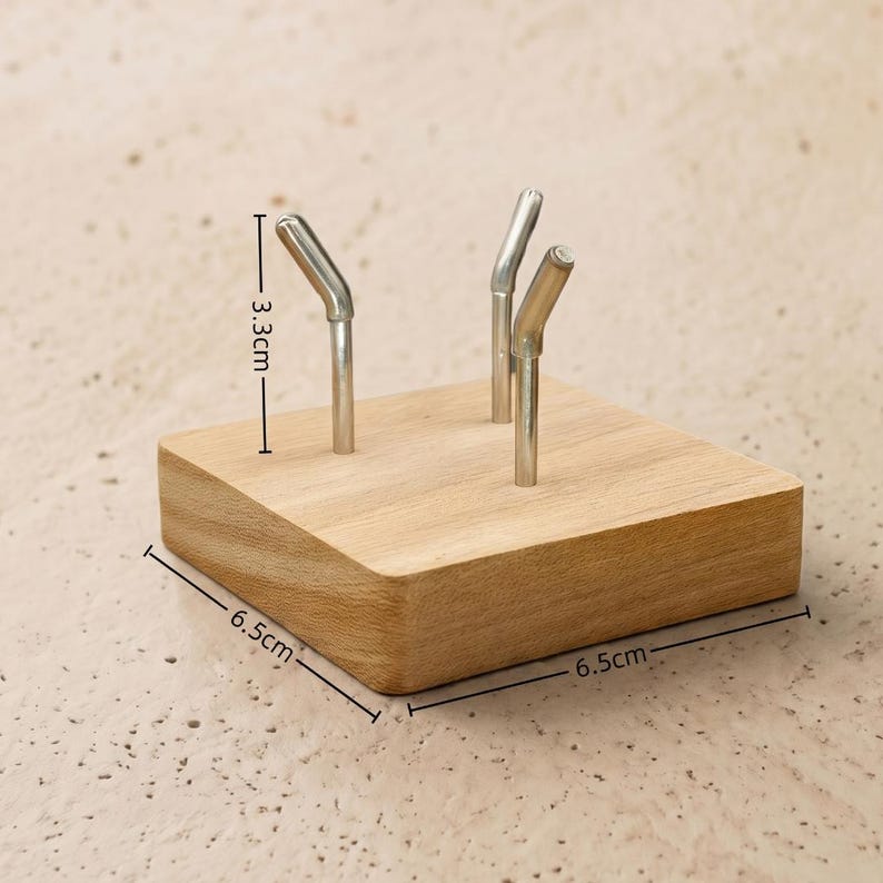Op de afbeelding: Een houten bureau-organizer met drie metalen penhouders. De houten basis meet 6,5 cm x 6,5 cm en de penhouders zijn 3,3 cm hoog. De organizer is gemaakt van lichtgekleurd hout.