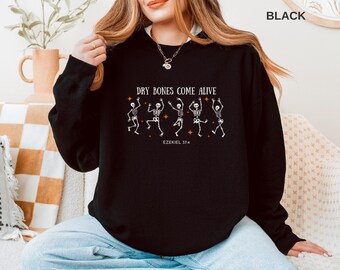 May include: Black sweatshirt with the text "DRY BONES COME ALIVE" and dancing skeleton graphics. The sweatshirt also includes the Bible verse Ezekiel 37:4. The design is in white.