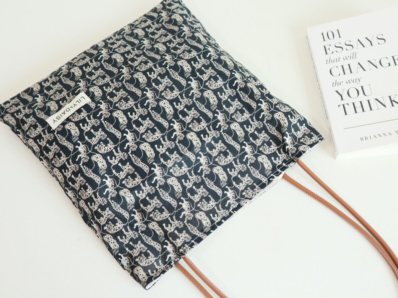 May include: A black tote bag with a white and black leopard print design. The bag has brown straps and a white label that says "Lily & Daisy".