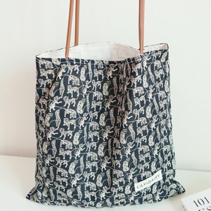 May include: Black tote bag with a white leopard print and brown leather straps. The bag has a white label with the text "LILY&DAISY" on it.