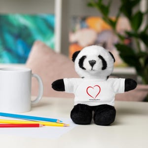 May include: A black and white panda bear plush toy wearing a white t-shirt with a red heart and the text "#veganlove" printed on it.
