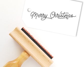 May include: A wooden stamp with a black ink pad and a wooden handle. The stamp reads "Merry Christmas" in a cursive font.