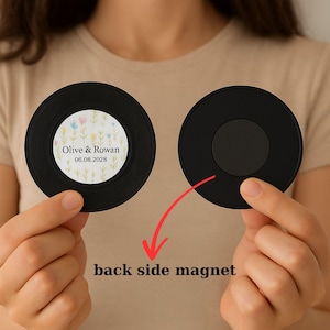 Può includere: Due magneti rotondi neri. Uno ha un centro bianco con i nomi "Olive & Rowan" e la data "06.08.2028" circondati da un motivo floreale. L'altro magnete mostra il retro. Il testo recita "back side magnet".