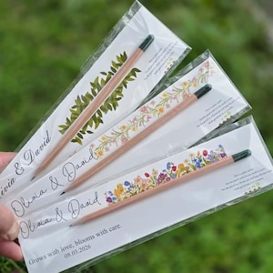 Top-down view of plantable seed pencils attached to custom printed floral cards inside clear plastic sleeves.