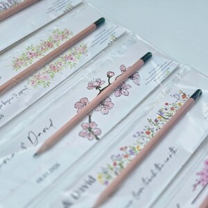 Natural light illuminating a rustic event souvenir consisting of a wooden writing tool and a floral printed paper sleeve.