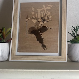May include: A framed wood carving of a character from the anime Demon Slayer. The character is in a fighting pose, holding a sword. The character is wearing a boar mask and has a kanji character on the background.