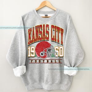 May include: Gray sweatshirt with a vintage-style graphic of a football helmet and the text "Kansas City 19 50 Football".
