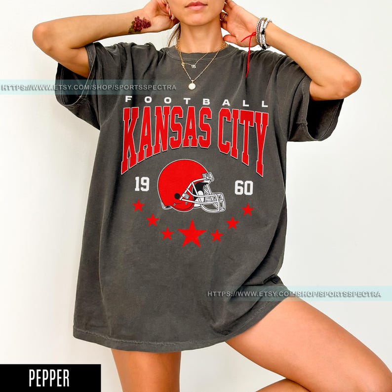 May include: An oversized grey t-shirt with a vintage-style graphic of a football helmet and the text "Football Kansas City 19 60".